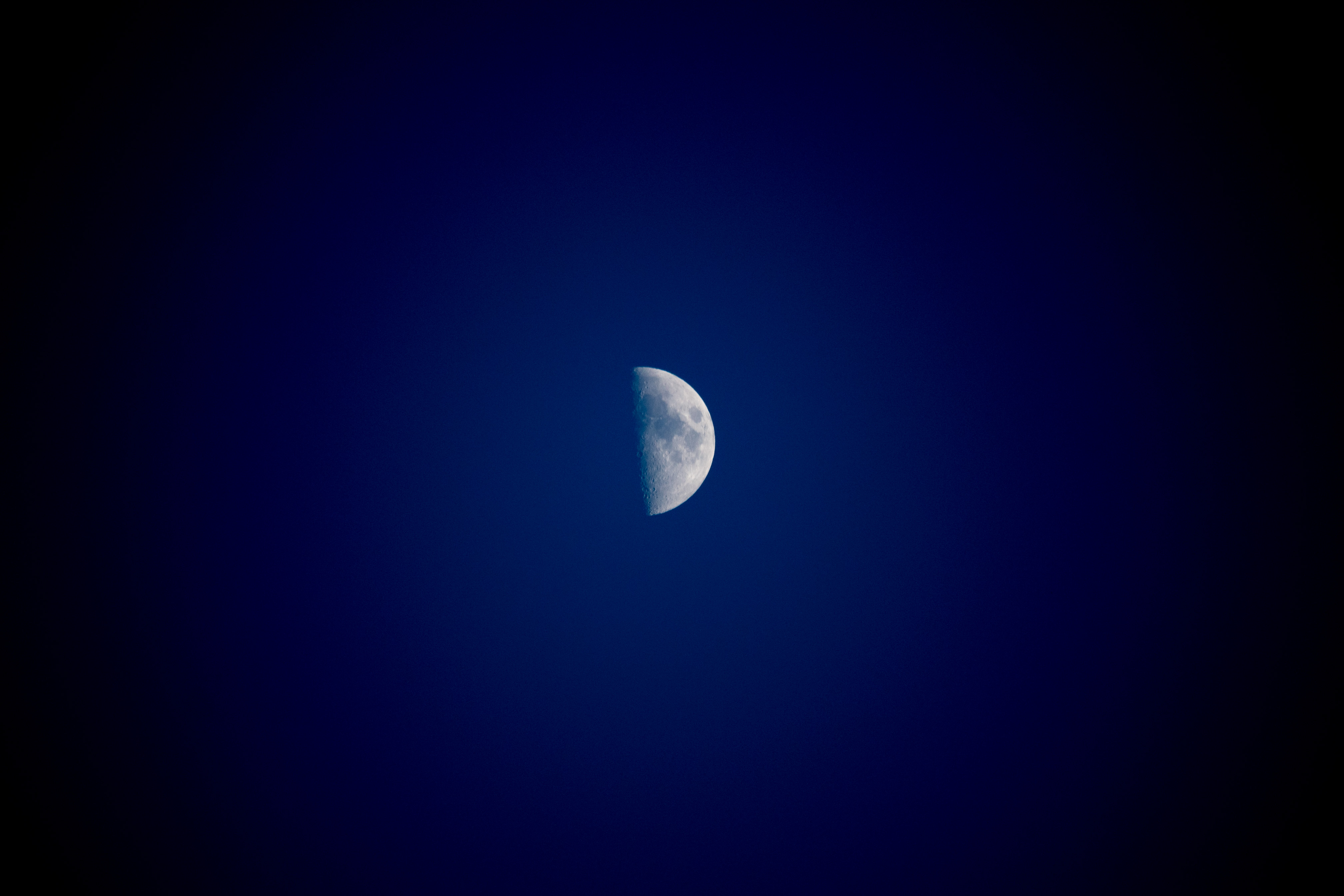 Pale half-moon against a blue background with strong vignetting