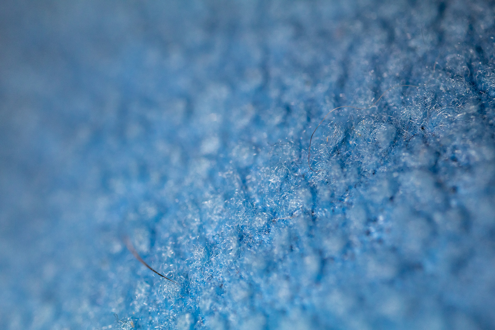 Extreme close-up of blue fabric with a small amount of animal fur clinging to it