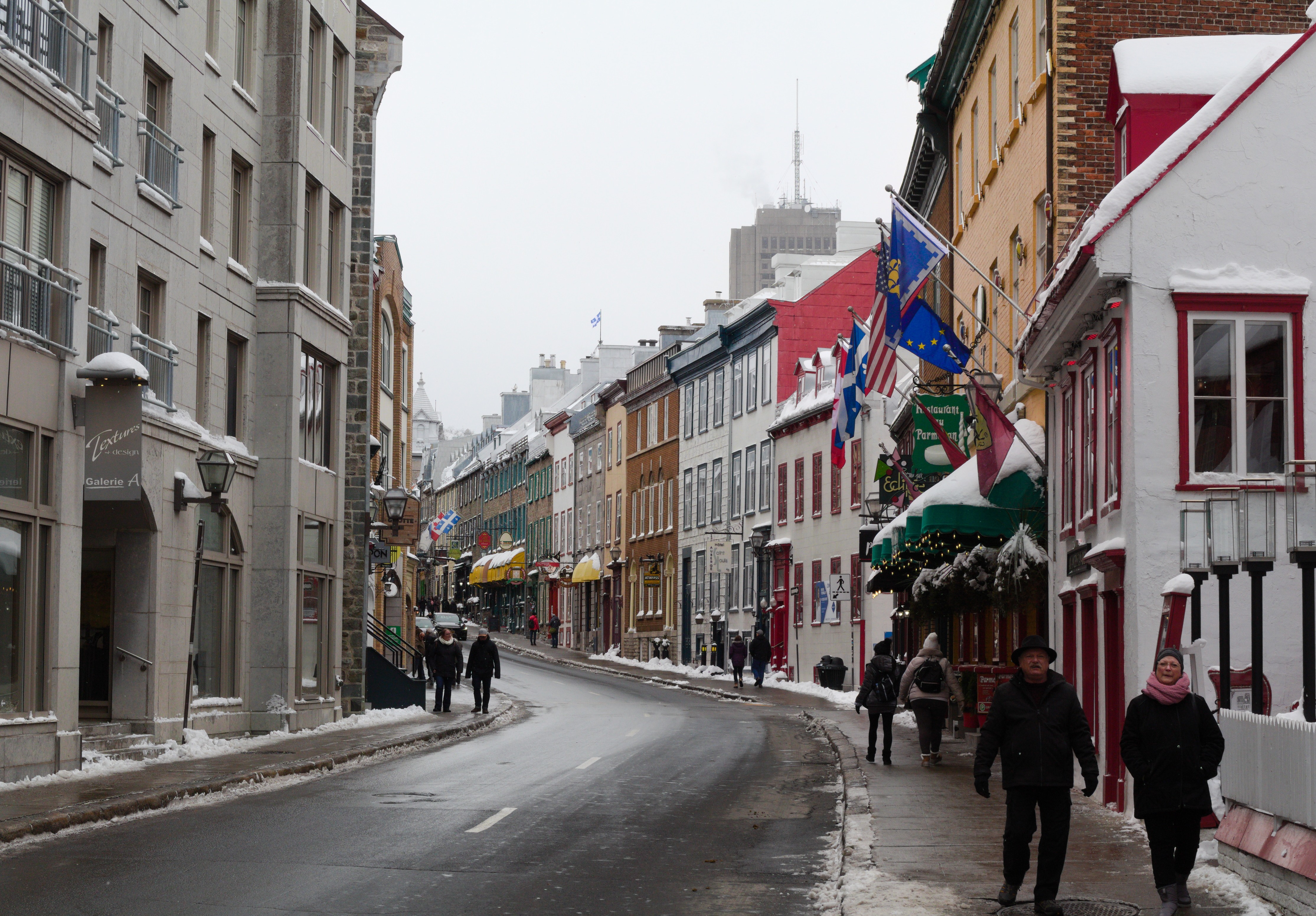 Street lined with colourful buildings; there are traces of snow on the street and sidewalk